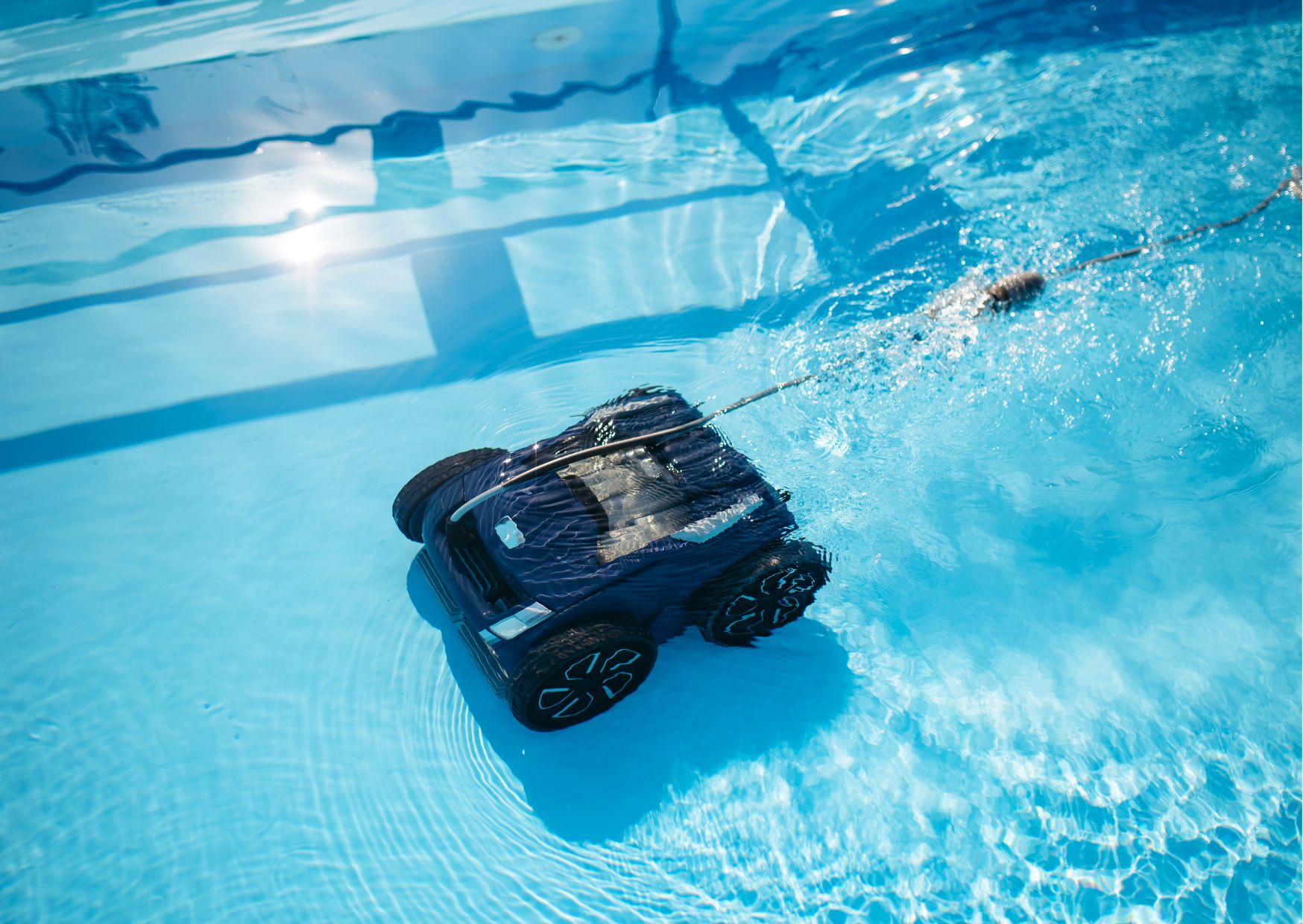 Robot per pulire la piscina in funzione sul fondo della vasca, con cavo galleggiante collegato, mentre aspira sporco e detriti nell’acqua Resto in attesa di conferma, grazie e buon lavoro